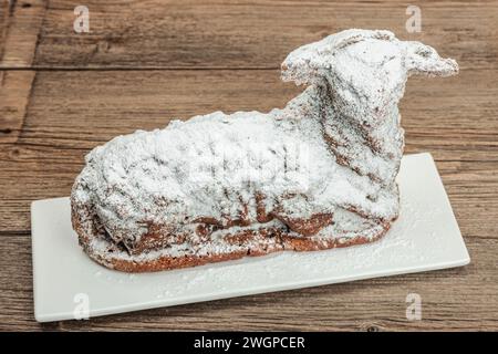 Easter lamb cake with traditional spring decor. Baked sweet dessert with sugar icing. Festive background, classic holiday symbols. Wooden background, Stock Photo