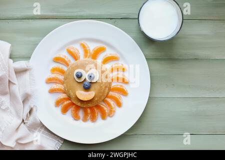 Fun, colorful creative pancake sun for children with banana and blueberry eyes, oranges for sunbeams and smile to encourage kids to eat healthy food. Stock Photo