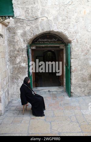 Courtyard of the Church of the Holy Sepulchre, Coptic monk sitting in front of the door of the Coptic Church in Jerusalem, Israel Stock Photo