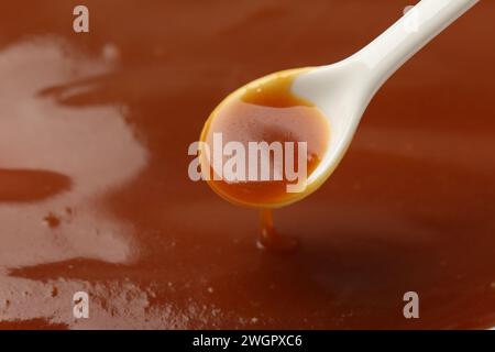 Taking tasty salted caramel with spoon, closeup. Space for text Stock Photo