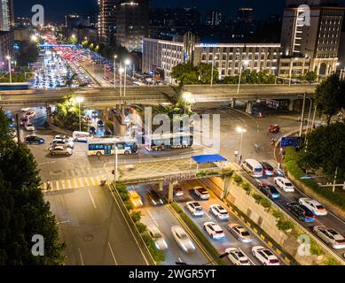 A nighttime aerial photo of a roundabout filled with vehicles, where the overpass and underground tunnel intersect. Wuhan, China Stock Photo