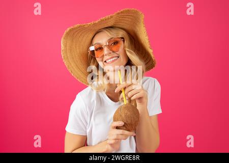 Portrait of cheerful blonde young lady holding coconut cocktail drink Stock Photo