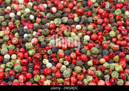 Background image. Top view of a mix of red, green, black, gray and white peppercorns. Stock Photo