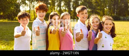 Group of happy children playing on good summer day and showing thumbs up together Stock Photo
