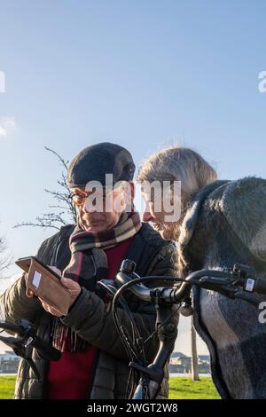 Elderly Couple going for a bike ride to keep fit and healthy in their retirement. Using the phone to navigate home Stock Photo