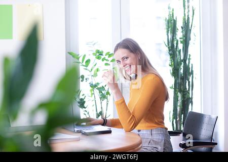 young woman in a room with green plants, home office Stock Photo