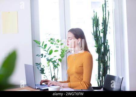 young woman in a room with green plants, home office Stock Photo