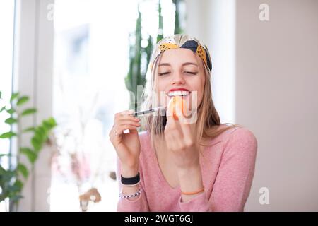 young woman with blond hair practices make-up with an egg Stock Photo