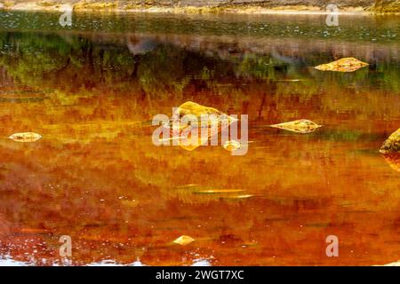 Striking layers of earth and a vivid streak of red water line the cracked ground of the Rio Tinto Stock Photo