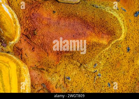 Striking layers of earth and a vivid streak of red water line the cracked ground of the Rio Tinto Stock Photo