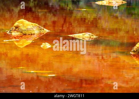 Striking layers of earth and a vivid streak of red water line the cracked ground of the Rio Tinto Stock Photo