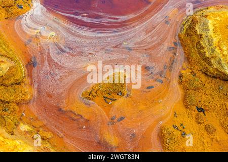 Striking layers of earth and a vivid streak of red water line the cracked ground of the Rio Tinto Stock Photo