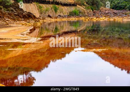 Striking layers of earth and a vivid streak of red water line the cracked ground of the Rio Tinto Stock Photo