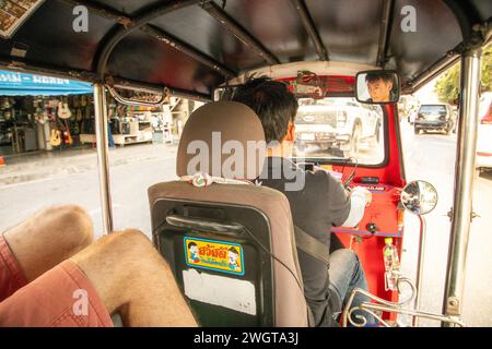Tourists riding in the back of Tuk Tuk Taxi through Chiang Mai in Northern Thailand Stock Photo