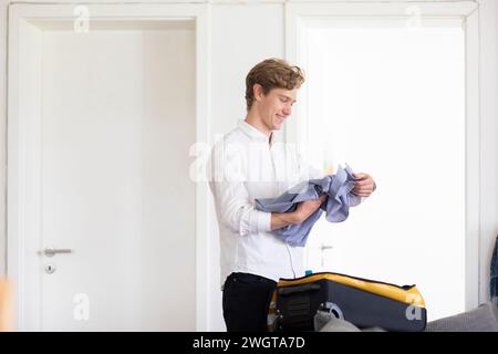 Young man packs suitcases at home Stock Photo