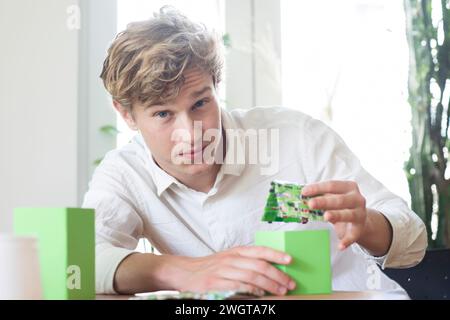Young man building a green energy house model Stock Photo