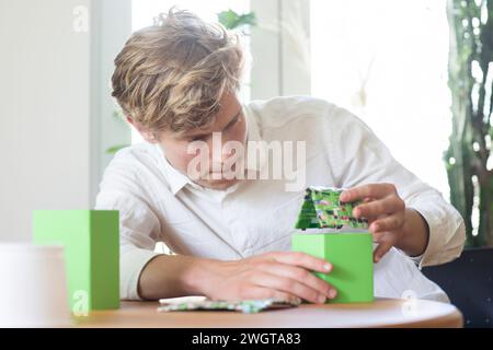 Young man building a green energy house model Stock Photo