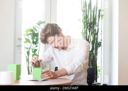 Young man building a green energy house model Stock Photo
