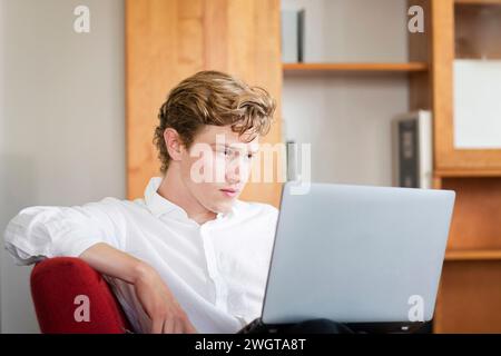 Young man sitting with laptop at home Stock Photo
