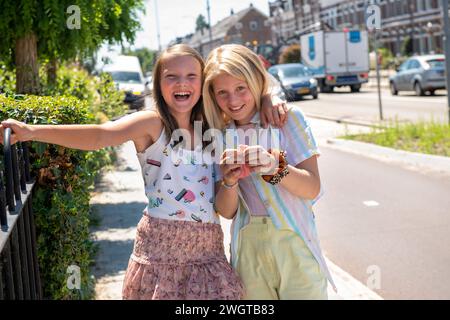 Young girls in the street playing and joking around walking in public Stock Photo
