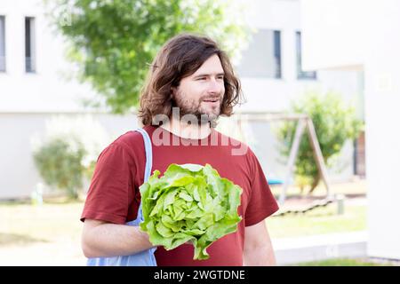 young man with a salad and a bag walking home Stock Photo