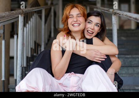 two young women sitting and hugging Stock Photo