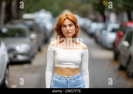 portrait of young redhead woman standing in the street Stock Photo