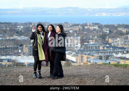 Edinburgh, Scotland, UK. 6th February 2024. Visitors on Calton hill wrapped up against the cold blustery wind and changeable weather conditions with views across the city rooftops looking north over the Forth estuary to Fife. Credit: Craig Brown/Alamy Live News Stock Photo