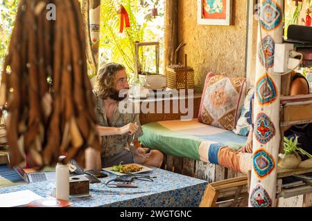 Young Man, traveller chatting with friends  and eating food in a restaurant in Northern Thailand Stock Photo
