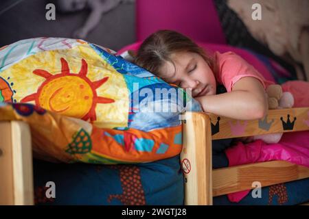 Young girl asleep peacefully on her bed surrounded by teddies Stock Photo