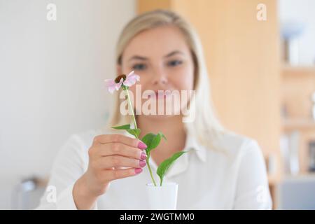 Woman with long blond hair putting a flower in vase Stock Photo