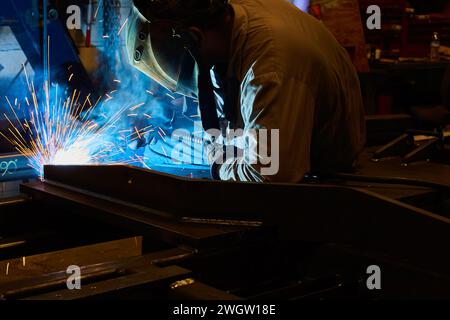 Welder at Work in Industrial Workshop with Bright Sparks Stock Photo