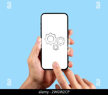 Adjusting mobile phone settings, smartphone cogwheel icon on screen Stock Photo