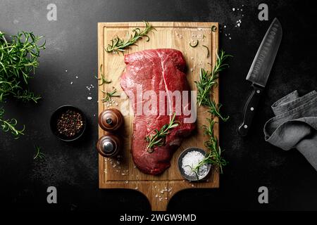 Beef meat entrecote on a cutting board, raw beef meat fillet on black background, top view Stock Photo
