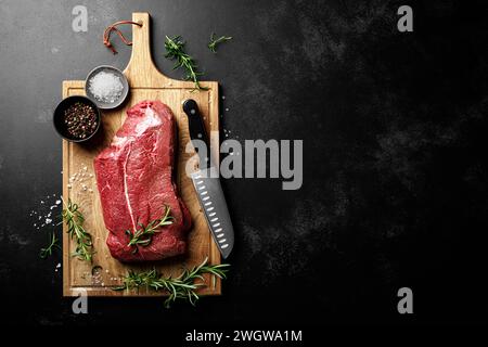 Beef meat entrecote on a cutting board, raw beef meat fillet on black background, top view Stock Photo