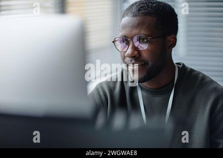 Closeup portrait of professional Black young man wearing glasses with computer screen reflection in office copy space Stock Photo