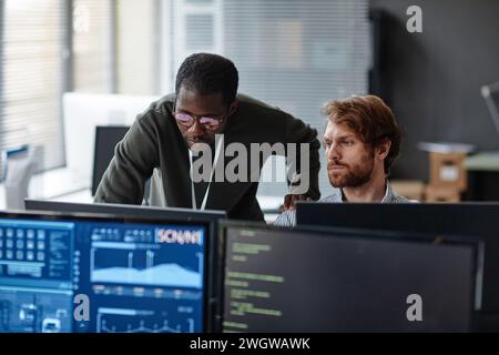 Portrait of two male professionals discussing work issues over computer monitors in cybersecurity office copy space Stock Photo