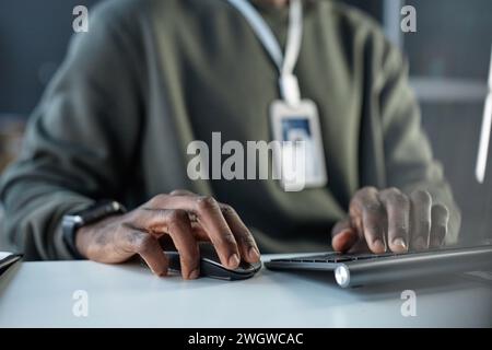 Close up of unrecognizable Black man using computer in office with focus on male hands using keyboard and mouse copy space Stock Photo