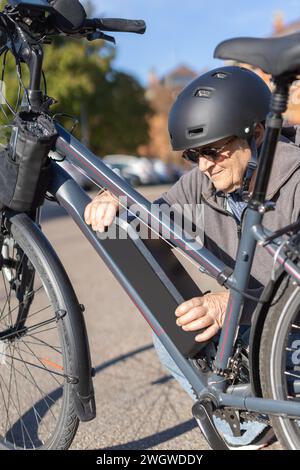 granny cyclist changing battery on e-bike Stock Photo