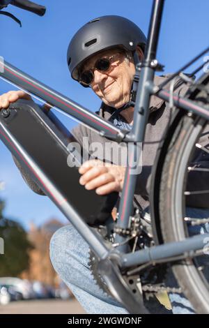 elderly woman changing battery on electric bicycle Stock Photo