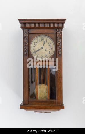 Old pendulum clock on a white wall. Stock Photo