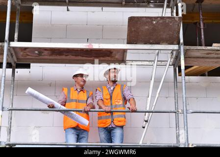 construction manager and architect on site during the construction of a house - planning and control on site - teamwork Stock Photo