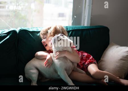 Toddler girl playing with her dog. Kids and pets concept. Little girl giggling with french bulldog. Child playing with dog Stock Photo
