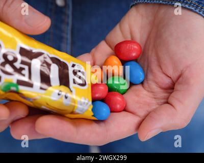 Tambov, Russian Federation - January 23, 2024 A woman pouring M&Ms in to her hand from a packet. Stock Photo