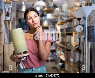 Asian woman choosing table lamp at store Stock Photo