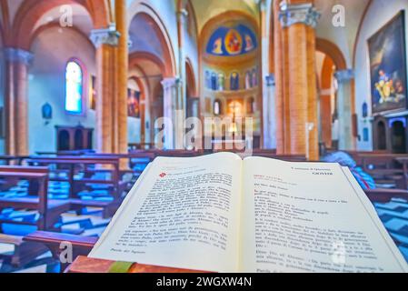 PIACENZA, ITALY - APRIL 6, 2022: The open Book of the Gospels against historic interior of Santa Brigida d'Irlanda Church, Piacenza, Italy Stock Photo