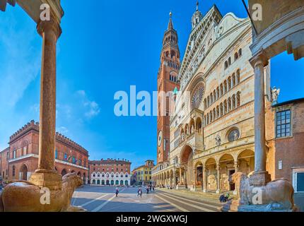 The tall pillars and stone statues of lions on the porch of Baptistery against thhe Santa Maria Assunta Cathedral, Piazza del Comune Square, Cremona, Stock Photo