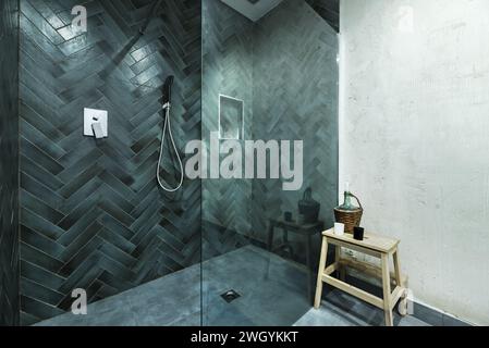 A large shower cubicle with green tiled tempered glass screen and gray floor Stock Photo