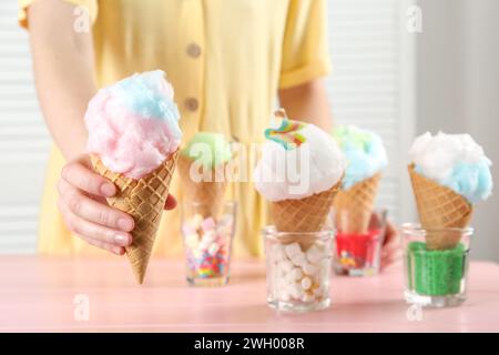 Woman holding waffle cone with cotton candy indoors, closeup Stock Photo