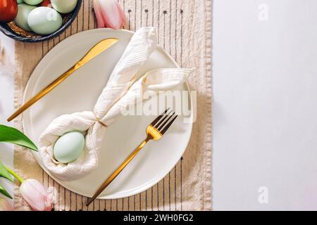 Easter themed table setting, with napkin folded in shape of a rabbit and blue egg, top view Stock Photo